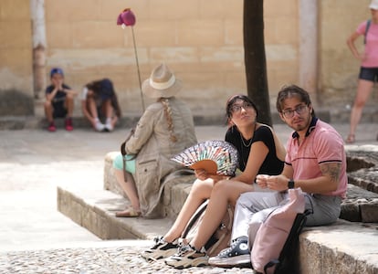 Dos personas se abanican, a la sombra, en el Patio de los Naranjos.