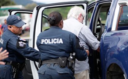Policías conducen al interior de un vehículo de la institución al hombre indicado de disparar en medio de las protestas de el martes en Ciudad de Panamá (Panamá).