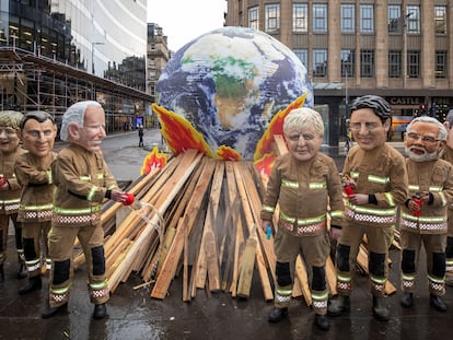 Activistas posan como líderes mundiales disfrazados de bomberos durante el último día de la COP26, en Glasgow.