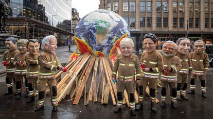 Activistas posan como líderes mundiales disfrazados de bomberos durante el último día de la COP26, en Glasgow.