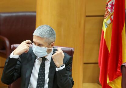 El ministro de Interior, Fernando Grande-Marlaska, se coloca la mascarilla durante su comparecencia ante la Comisión de Interior en el Senado.