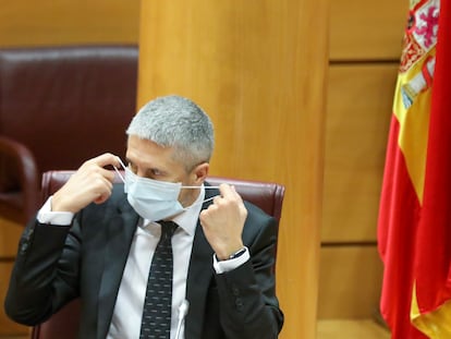 El ministro de Interior, Fernando Grande-Marlaska, se coloca la mascarilla durante su comparecencia ante la Comisión de Interior en el Senado.
