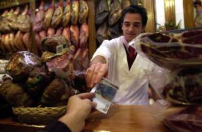 Un dependiente de una charcutería del Mercado Central de Valencia recibe de un cliente un billete de 20 euros. EFE/Archivo