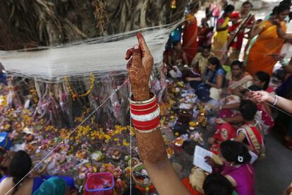 Mujeres indias casadas atan hilos de algodón alrededor de un árbol de Banyan mientras realizan rituales en el primer día de la fiesta Vat Savitri en Ahmedabad (India).