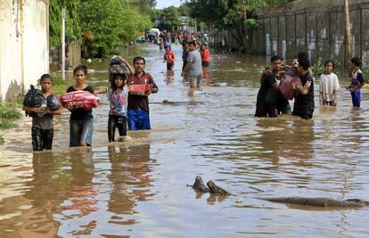 Decenas de personas portan sus pertenencias mientras recorren las calles inundadas por las fuertes precipitaciones caídas sobre Dili, la capital de Timor Oriental.
