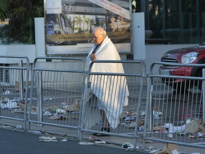 Un hombre envuelto en una colcha observa el lugar del atentado en el Paseo de los Ingleses de Niza, Francia.
