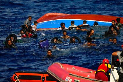 Varios migrantes se mantienen a flote sujetos a flotadores mientras durante el rescate. 