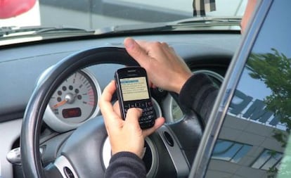 Un conductor utiliza un tel&eacute;fono m&oacute;vil durante la conducci&oacute;n.