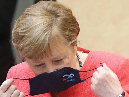 La acnciller alemana Angela Merkel se quita la mascarilla antes de un discurso en el Parlamento alemán. 