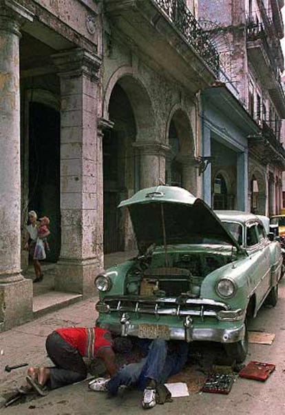 Dos cubanos reparan su coche en una calle de La Habana Vieja.