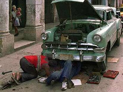 Dos cubanos reparan su coche en una calle de La Habana Vieja.