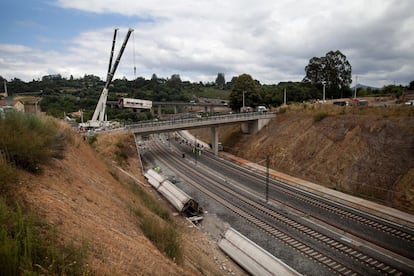Dos grúas de grandes dimensiones trabajan en la zona del accidente para quitar los vagones de las vías del tren cerca de Santiago de Compostela.