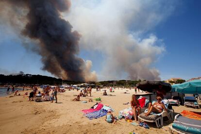 El cielo se llena de humo por un incendio mientras los turistas disfrutan en la playa de Bormes-les-Mimosas (Francia), el 26 de julio de 2017.