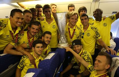 Los jugadores del Sevilla posan con el trofeo en el avión que los trajo de Turín.