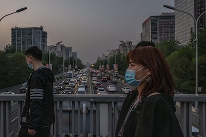 Transeúntes sobre una carretera llena de coches circulando en hora punta, este lunes en Pekín, China.