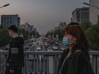 Transeúntes sobre una carretera llena de coches circulando en hora punta, este lunes en Pekín, China.