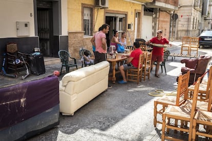 Vecinos de la localidad de Dolores (Alicante) comen una paella en el exterior de su vivienda, afectada por las inundaciones.