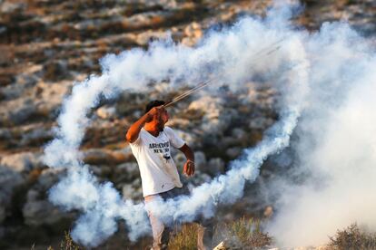 Un manifestante palestino utiliza una honda para arrojar un bote de gas lacrimógeno de vuelta hacia las fuerzas de seguridad israelíes durante los enfrentamientos en la aldea de Ras Karkar, en Cisjordania.
