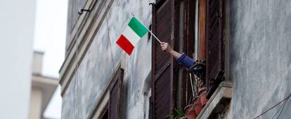 Una persona confinada en casa ondea una bandera italiana en Roma.