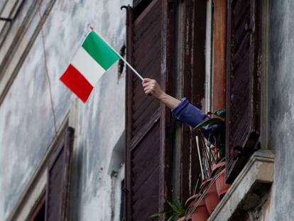 Una persona confinada en casa ondea una bandera italiana en Roma.