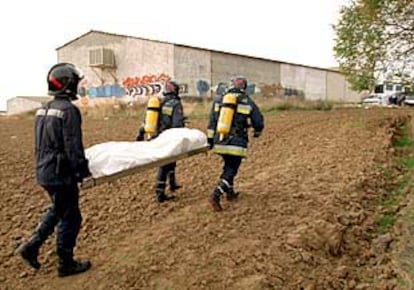 Bomberos de Fuenlabrada trasladan uno de los cadáveres encontrados en un cobertizo.