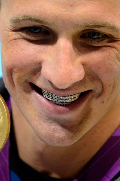 El pasado día 28 el guapísimo (y deseado por las marcas) nadador estadounidense Ryan Lochte recogía su medalla de oro en los 400 metros estilos con un curioso accesorio. En su sonrisa asomaba una bandera de Estados Unidos formada por piedras que le daban un toque entre hortera y simpático. Es un grill, una pieza de joyería que hasta hace poco no salía de la estética del hip hop y que últimamente muchos famosos de distinto pelo se ponen como un accesorio más. El grill se coloca sobre los dientes como una suerte de funda, aunque también los hay fijos. Pueden estar elaborados de oro, platino, con piedras preciosas y suelen ser un signo de ostentación. Lo normal es quitárselos para comer para que no te pase como a un niño de 7 años que en su día se tragó uno.