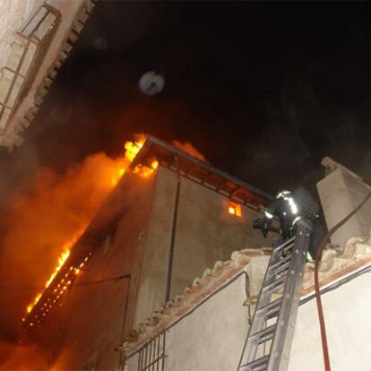 Un bombero intenta aliviar el fuego desde una azotea colindante.