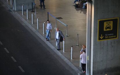 Varias personas esperan la llegada de taxis en el aeropuerto madrileño de Barajas.