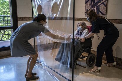 Reyes González abrazando a Marixu, su madre, en la residencia Ballesol Príncipe de Vergara. Usan un arco con plástico para poder tener contacto físico mientras previenen posibles contagios de covid-19. 
