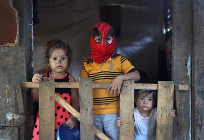 Un grupo de niños posa en la puerta de su casa, donde solo hay una habitación.