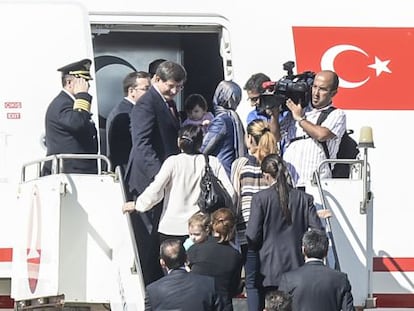 O primeiro-ministro turco, Ahmed Davutoglu (acima à esquerda), recebe os reféns libertados, em um avião em Sanliurfa.