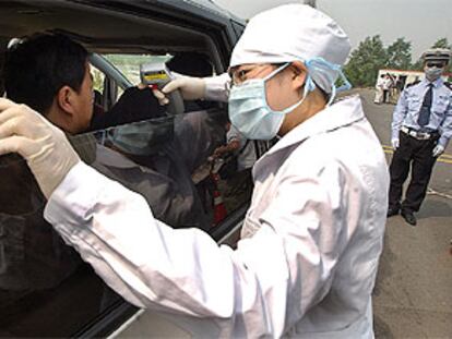 Un médico toma la temperatura a los pasajeros que salen del aeropuerto de Pekín.