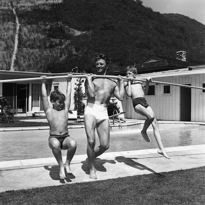 Kirk Douglas usa una pértiga para levantar a sus hijos Joel y Michael en la piscina de su casa.