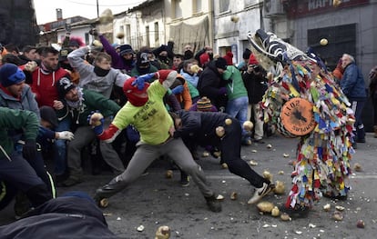 Varias personas tiran nabos a un hombre que representa al Jarrampla, disfrazado con cintas multicolores y una máscara cómica, durante las festividades anuales de San Sebastián, en Piornal (España).