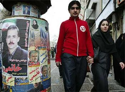 Una pareja pasea ante  carteles electorales ayer en Teherán.