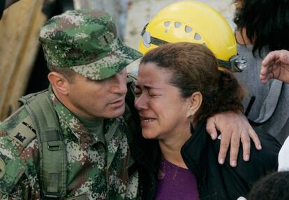 Un oficial de policía consuelo a una mujer en la localidad de Bello. Al menos 12 cuerpos han sido recuperados del lodo en la zona y más de 145 personas han fallecido por las fuertes lluvias de esta semana.