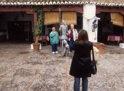 Turistas fotografiándose junto a una estatua de Don Quijote en el pozo de la Venta del Quijote, en Puerto Lápice.