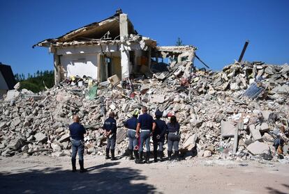 Agente de policía observan los restos de un edificio que fue destruido durante un terremoto en Amatrice (Italia).