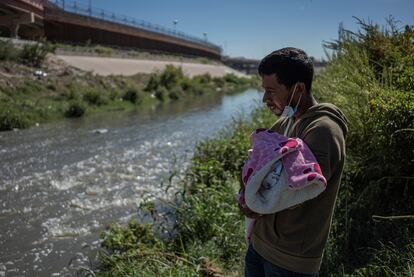 Un migrante con su hijo en brazos se prepara para cruzar el río Bravo en Ciudad Juárez.