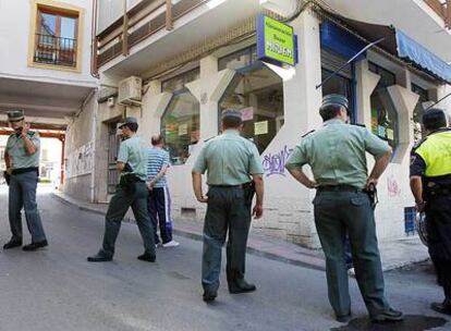 Cuatro agentes de la Guardia Civil y un policía local rodean la tienda donde se produjo el asesinato.