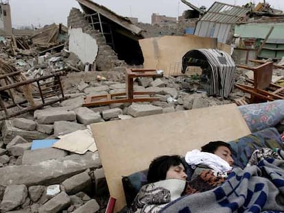 Una pareja duerme entre los escombros y restos de muebles en una vivienda derruida por el terremoto del miércoles, en la ciudad de Pisco.