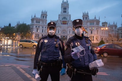 Policías municipales ofrecen mascarillas en la plaza de la Cibeles, en Madrid, este lunes.