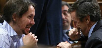 Pablo Iglesias y Rafael Hernando hablan en el hemiciclo del Congreso.