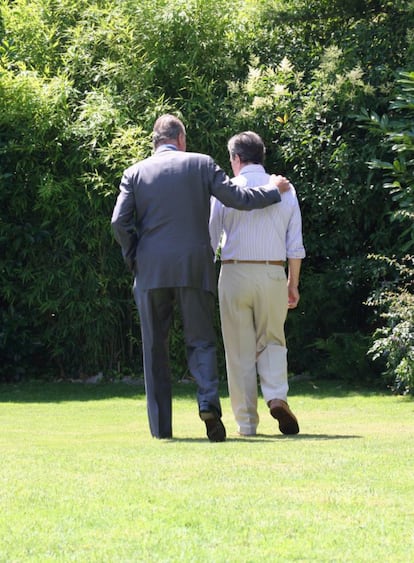 Juan Carlos I pasea el 16 de julio de 2008 con el expresidente del Gobierno Adolfo Suárez, enfermo de alzhéimer, en los jardines de su vivienda de Madrid durante la visita en la que los Reyes le entregaron el Toisón de Oro, en una foto difundida por la familia. La fotografía fue galardonada con el Premio Ortega y Gasset.