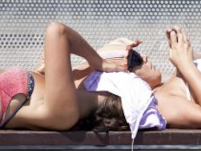 Dos mujeres protegiéndose del sol en un banco de Barcelona.