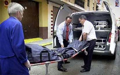Operarios introducen en un furgón el cadáver de una mujer de Aldaia, de 28 años, asesinada por su marido, de 30, del que se había separado tras denunciarlo por malos tratos. La pareja tenía tres hijos.