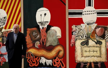 El pintor Eduardo Arroyo posa junto a su obra 'Los cuatro dictadores', que forma parte de la nueva sección de la colección permanente del Museo Reina Sofía, presentada hoy, lunes 21 de mayo, bajo el titulo '¿La guerra ha terminado? Arte en un mundo dividido (1945-1968)', que recorre las transformaciones artísticas en la posguerra con obras de Francis Bacon, Philip Guston, Darío Villalba, Jean Tinguely, Yves Klein, Raimond Hains, Eduardo Arroyo o Val del Omar.