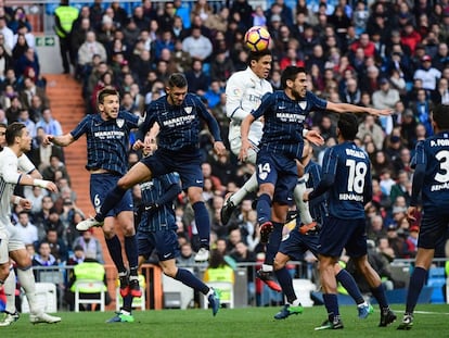 Varane del Real Madrid cabecea ante los jugadores del Málaga José Luis y Recio.