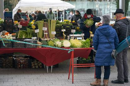 Dos personas frente a un puesto en un mercado de Vitoria.