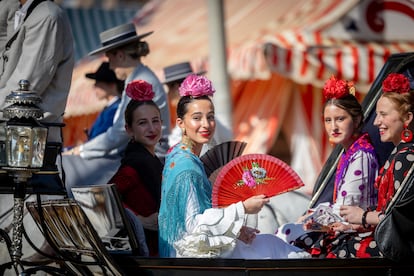Varias chicas pasean en carruaje aliviando el calor con abanicos, este lunes en Sevilla.